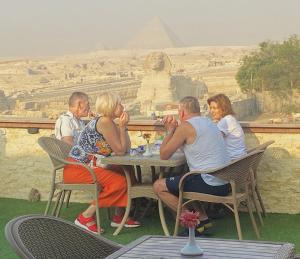 um grupo de pessoas sentadas numa mesa em frente à pirâmide em Seven Pyramids Inn em Cairo