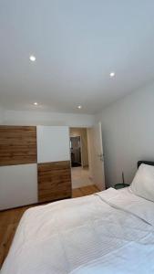 a bedroom with a white bed with a wooden dresser at Gartenwohnung neben dem LKH in Graz