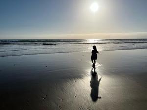 Una mujer caminando por una playa con el océano en Mar de Crystal, en Puerto Nuevo