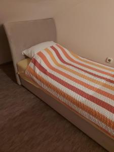 a bed with an orange and white striped blanket on it at Apartman Kovači in Sarajevo