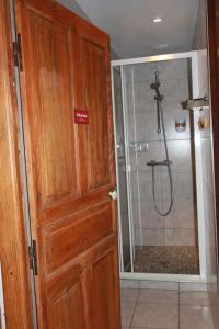 ein Badezimmer mit einer Dusche und einer Holztür in der Unterkunft Gîte le Clou in Thiézac