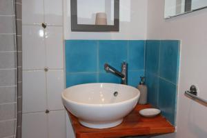 ein Badezimmer mit einem weißen Waschbecken auf einer Holztheke in der Unterkunft Gîte le Clou in Thiézac