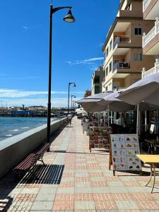 una acera con mesas y sombrillas junto a un edificio en Casa Veronica 4 , 1 Dormotorio, en Arona 29 fotos más