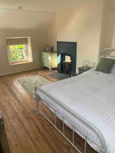 a bedroom with a white bed and a fireplace at Character Cottage Nr Betws Y Coed. in Betws-y-coed