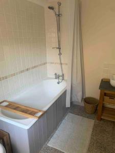 ein Badezimmer mit einer weißen Badewanne und einer Dusche in der Unterkunft Character Cottage Nr Betws Y Coed. in Betws-y-coed
