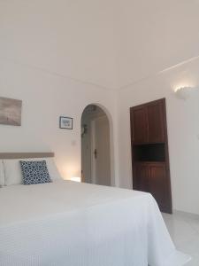 um quarto branco com uma cama branca e um armário de madeira em L'Archetto romantic suite in the center of Anacapri em Anacapri
