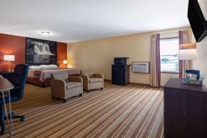 a hotel room with a bed and a desk and chairs at Super 8 by Wyndham Mattoon in Mattoon