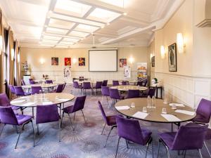 ein Restaurant mit Tischen, lila Stühlen und einer Tafel in der Unterkunft Hotel Mercure La Baule Majestic in La Baule