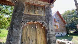 una gran puerta de madera frente a una casa en Complexul Turistic Căsuțele din grădină: Căsuța cu Stuf, en Marga