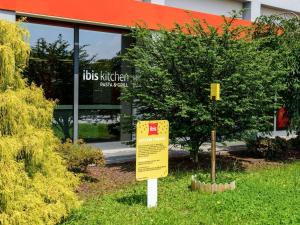 a sign in the grass in front of a building at Ibis Milano Fiera in Lainate