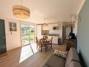een woonkamer met een bank en een tafel en een keuken bij Séjour paisible en famille proche de la nature - logement avec terrasse et aire de jeu in Lesperon