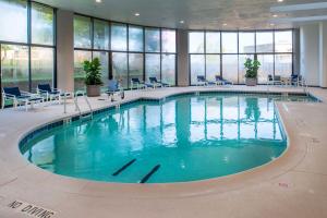 a large swimming pool in a building with windows at Hilton St. Louis Airport in Woodson Terrace