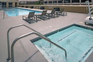 una gran piscina con sillas y una bañera de hidromasaje. en DoubleTree by Hilton Modesto en Modesto