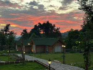 a house with a sunset in the background at Antaraal Resort & Spa A Village Resort in Dharamshala