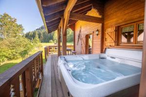 duża wanna z hydromasażem na drewnianym tarasie w obiekcie Les Griottes, véritable chalet de montagne, avec Jacuzzi et Sauna w mieście Xonrupt-Longemer