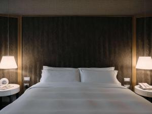 a bedroom with a large white bed with two lamps at Manto Hotel Lima - MGallery in Lima