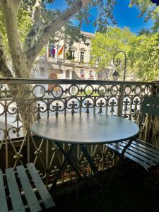 uma mesa sobre uma cerca de ferro forjado com um banco em Ô portes du Palais em Avignon