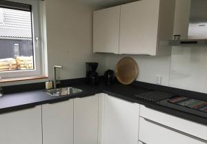 a kitchen with white cabinets and a sink and a window at Bungalow 71 op Recreatiepark De Wielen in Sint Maarten