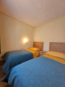 - 2 lits dans une chambre de couleur bleue et jaune dans l'établissement Kamp Brda Camping and rooms, à Kojsko