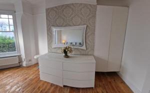 a white dresser in a room with a mirror at Peaceful well equipped flat near central London in London