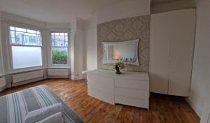 ein Wohnzimmer mit einer weißen Kommode und 2 Fenstern in der Unterkunft Peaceful well equipped flat near central London in London