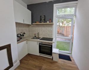 eine kleine Küche mit einem Waschbecken und einem Fenster in der Unterkunft Peaceful well equipped flat near central London in London