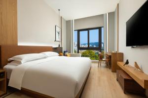 een slaapkamer met een wit bed en een flatscreen-tv bij voco Thousand Island Lake, an IHG Hotel in Qiandao-meer