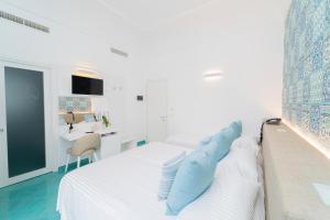 a white bedroom with a bed with blue pillows on it at Hotel Miramare in Maiori