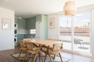 een keuken met een houten tafel en stoelen en een groot raam bij atico reformado en madrid rio in Madrid