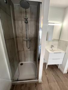a shower with a glass door next to a sink at Au pied du Tramway in Ambilly