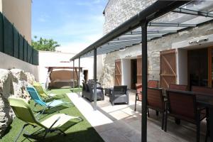 un patio al aire libre con sillas, mesa y parrilla en Belle maison de village sur theziers, en Théziers
