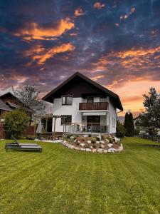 a house in a yard with a sunset in the background at Vila Minka Bled - Perfect Family Vacation Home in Bled