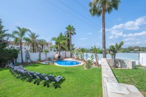 einen Garten mit Stühlen, einem Pool und Palmen in der Unterkunft Villa Jazz Marbella with 7 bedrooms in Marbella