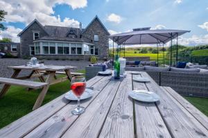 a wooden picnic table with a glass of wine on it at House - Private use in Sedbergh