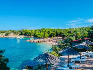 a beach with chairs and umbrellas and a body of water at Adria Holiday Home in Pinezici