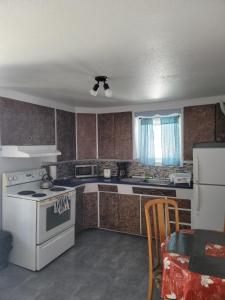 een keuken met een fornuis en een wit apparaat bij Cozy quiet place next to hwy smart tv+wifi+netflix in Edmundston