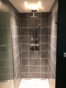 y baño con ducha de azulejos grises. en De Barg, en Vinkenbuurt