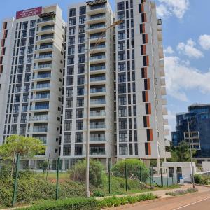 a tall white apartment building with two tall buildings at Intercultural Apartment Nairobi Two Rivers in Nairobi