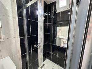 a black tiled bathroom with a shower with a toilet at STONE HOME Hostel in Istanbul