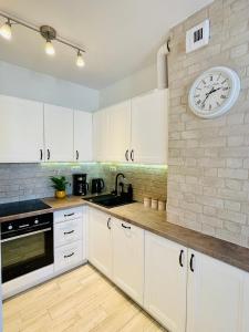 a kitchen with white cabinets and a clock on the wall at BeeApartments Naściszowska 18 in Nowy Sącz
