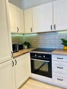 a kitchen with white cabinets and a black oven at BeeApartments Naściszowska 18 in Nowy Sącz