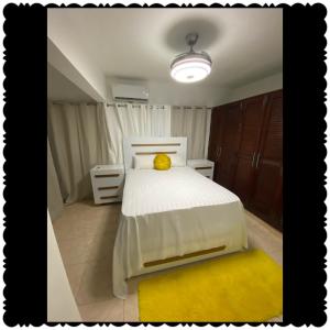 1 dormitorio con cama blanca y alfombra amarilla en Apartment city center of puerto Plata, en San Felipe de Puerto Plata