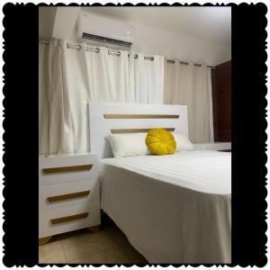 a bedroom with a white bed with a yellow pillow at Apartment city center of puerto Plata in San Felipe de Puerto Plata
