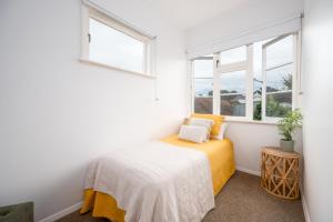 a bedroom with a bed and two windows at The Blue House in Havelock North