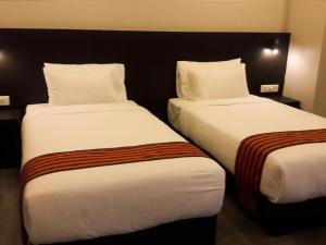 2 letti posti uno accanto all'altro in una camera d'albergo di Hotel Bhutan Ga Me Ga a Phuntsholing