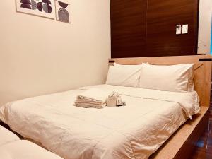 a bed with white sheets and a purse on it at Destina Stays, Cozy & Netflix @Air Residences, Makati, Metro Manila in Manila
