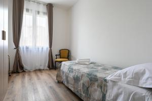 a bedroom with a bed and a chair and a window at Free parking 7 minutes from the Euganean Hills in Battaglia Terme