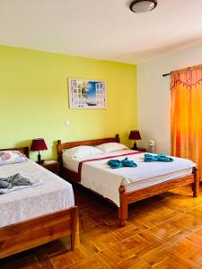 two beds in a bedroom with yellow walls and wooden floors at Casa BB&Djassi in Ponta do Sol