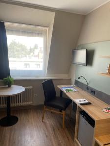een kamer met een bureau, een tafel en een raam bij Hotel Corsten in Heinsberg