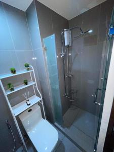 a bathroom with a shower with a toilet and a glass shower stall at Destina Stays, Cozy & Netflix @Air Residences, Makati, Metro Manila in Manila